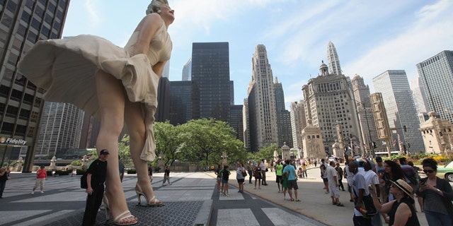 CHICAGO, IL - JULY 15: Spectators look at 'Forever Marilyn,' a sculpture by Seward Johnson, on July 15, 2011 in Chicago, Illinois. The stainless steel and aluminum sculpture which stands 26 feet tall and weighs 34,000 pounds will be on display in Chicago through the spring of 2012. The sculpture was inspired by Marilyn Monroe?s iconic scene in the 1955 movie Seven Year Itch. (Photo by Scott Olson/Getty Images)