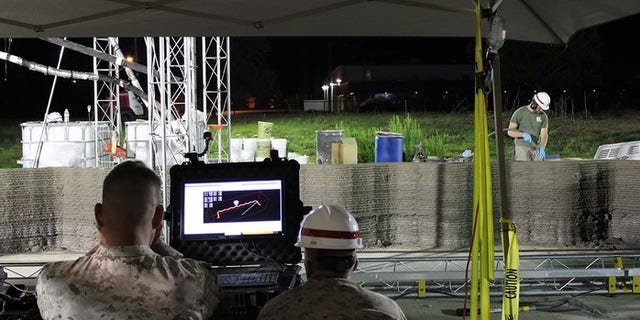Marines from I Marine Expeditionary Force monitor the computer while the world's largest concrete 3D printer constructs a 500-square-foot barracks hut at the U.S. Army Engineer Research and Development Center in Champaign, Illinois. (U.S. Marine Corps Courtesy Photo)