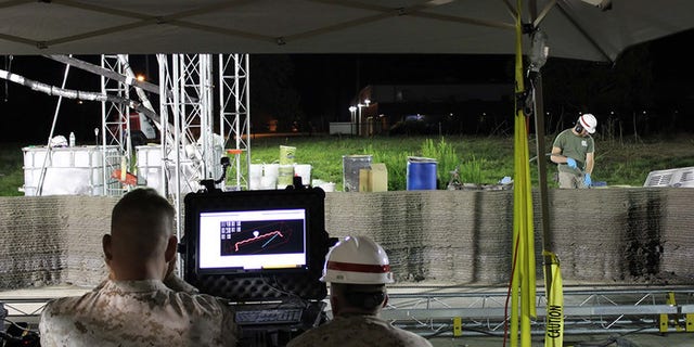 Marines from I Marine Expeditionary Force monitor the computer while the world's largest concrete 3D printer constructs a 500-square-foot barracks hut at the U.S. Army Engineer Research and Development Center in Champaign, Illinois. (U.S. Marine Corps Courtesy Photo)