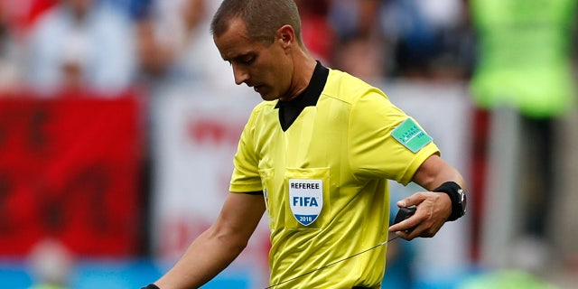 Referee Mark Geiger adjusts his ear piece used to communicate with his assistants during a group B match between Portugal and Morocco.