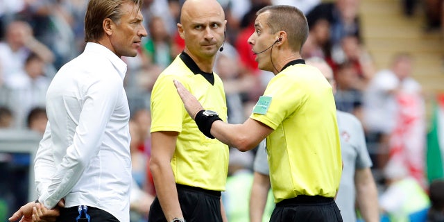 Referee Mark Geiger, right, talks to Morocco coach Herve Renard during a group B match between Portugal and Morocco.