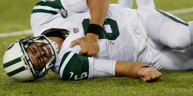 New York Jets quarterback Mark Sanchez (6) reacts to an injury during the second half of a preseason NFL football game against the New York Giants, Saturday, Aug. 24, 2013, in East Rutherford, N.J. He left the game with what appeared to be a shoulder injury. (AP Photo/Julio Cortez)