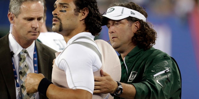 A trainer wraps New York Jets quarterback Mark Sanchez, center, during the second half of a preseason NFL football game against the New York Giants, Saturday, Aug. 24, 2013, in East Rutherford, N.J. (AP Photo/Julio Cortez)