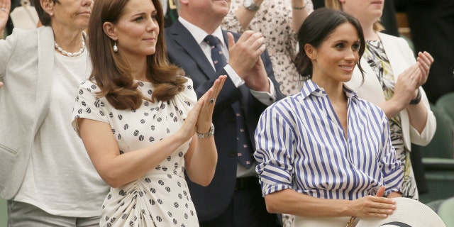 Duchess Kate Middleton and Meghan Markle watch the women's Wimbledon finale while Markle clings onto her straw hat she was unable to wear in the royal box on Saturday.