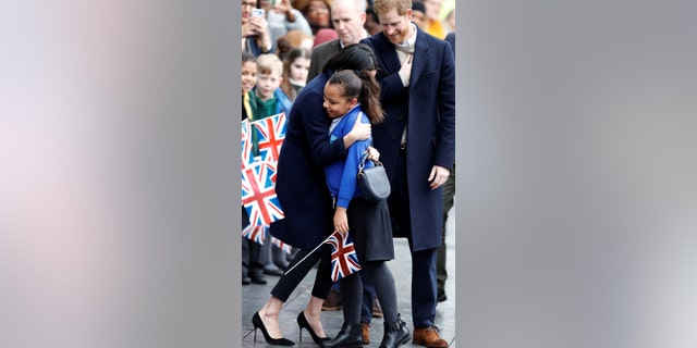 Markle and Prince Harry hug fans on the street.