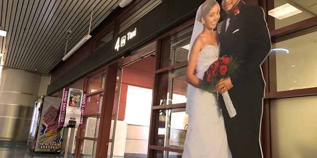 A cardboard cutout of a couple beckons real couples to come apply for a marriage license. It is conveniently placed near the taxi stand at McCarran Airport in Las Vegas.