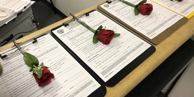 Roses are attached to marriage license applications waiting to be filled out. The licenses cost $77 at the pop-up marriage bureau kiosk at McCarran Airport in Las Vegas.