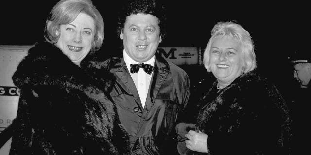 FILE - In this March 16, 1965, file photo, comedian Marty Allen, center, arrives for the premiere of "The Train" with his wife Frenchie, right, and Rosemary Wilson, wife of columnist Earl Wilson, in New York. Allen's spokeswoman Candi Cazau says he died Monday, Feb. 12, 2018, of complications from pneumonia. His wife and performing partner Karon Kate Blackwell was by his side. He was 95. (AP Photo/John Lent, File)