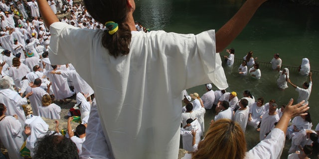 YARDENIT, ISRAEL - OCTOBER 01:  Brazilian Evangelist Christians raise their arms in prayer during their mass baptism ceremony in the Jordan River on October 1, 2007 at Yardenit in northern Israel. The group of 700 worshippers descended in the biblical river as part of their pilgrimage to the Holy Land.  (Photo by David Silverman/Getty Images)