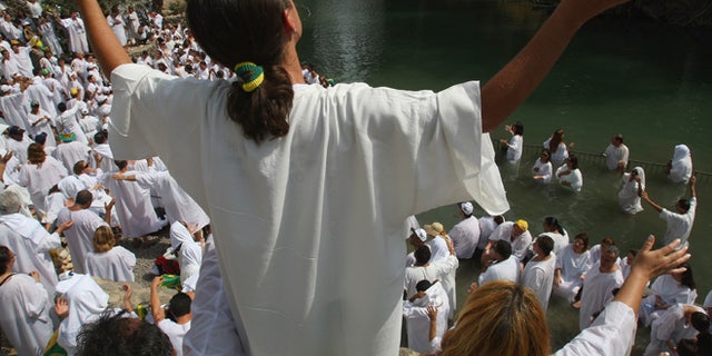 YARDENIT, ISRAEL - OCTOBER 01: Brazilian Evangelist Christians raise their arms in prayer during their mass baptism ceremony in the Jordan River on October 1, 2007 at Yardenit in northern Israel. The group of 700 worshippers descended in the biblical river as part of their pilgrimage to the Holy Land. (Photo by David Silverman/Getty Images)