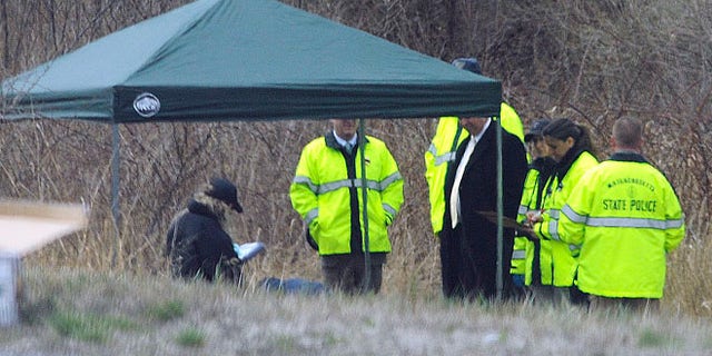 Apr. 18, 2014: Massachusetts State Police stand along Interstate 190 where police said a child's body was found near Sterling, Mass.