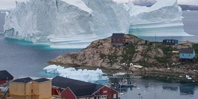 A massive iceberg is looming near a tiny village in Greenland.