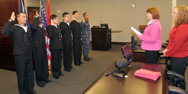 The first Navy Sailors to participate in the Secretary of Defense's Military Accessions Vital to National Interest pilot program are issued the oath of citizenship by Stacey Summers, branch chief from the U.S. Citizenship and Immigration Services Chicago field office in 2010.