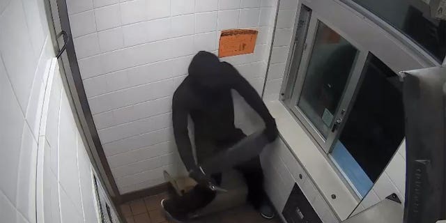 After climbing through the drive-thru, the masked gunman escaped with a cash register.