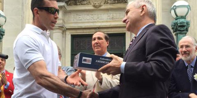 Green Beret P. Andrew McKenna, left, receives a flag that flew over the U.S. Capitol from Sen. Jack Reed (D-R.I.) at Bristol, R.I., Fourth of July parade. (Photo courtesy of Reed) .