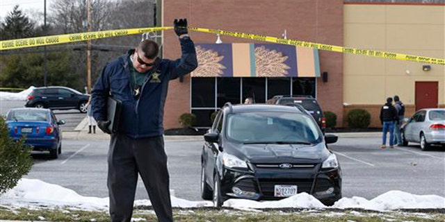 An investigator walks beneath a police tape line at the scene of a shooting at a shopping center in Abingdon, Md., Wednesday, Feb. 10, 2016. A man opened fire inside a shopping center restaurant during lunchtime. (AP Photo/Patrick Semansky)