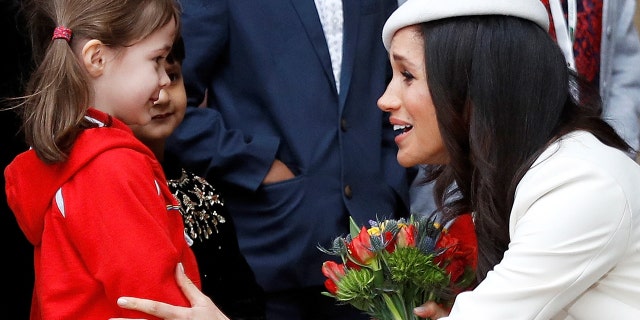 Markle recieves flowers from onlooker in front of Westminster Abbey.