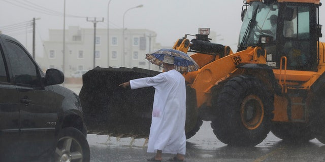 May 25, 2018: An Omani official gestures to a loader driver to tear away a road median to drain a flooded street in Salalah, Oman.