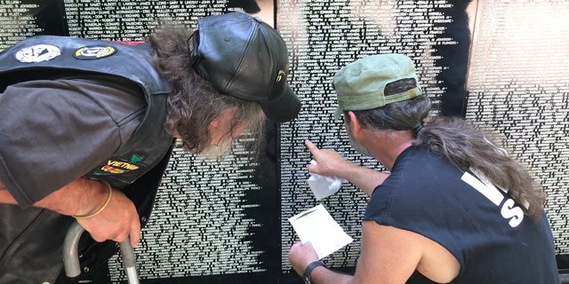 A Vietnam veteran receives help while searching for a fallen comrade's name on the Vietnam Traveling Memorial Wall.