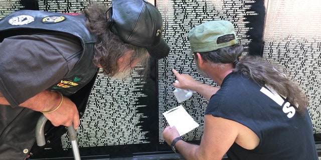 A Vietnam veteran receives help while searching for a fallen comrade's name on the Vietnam Traveling Memorial Wall.