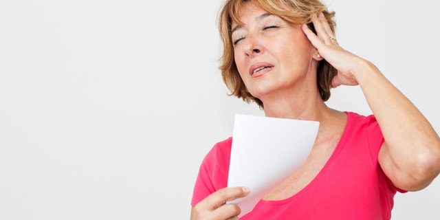 Woman cooling herself with a blank paper.