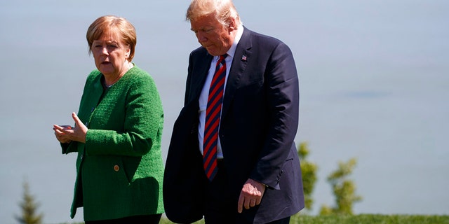 President Donald Trump, right, talks with German Chancellor Angela Merkel after the family photo during the G7 Summit, Friday, June 8, 2018, in Charlevoix, Canada. (AP Photo/Evan Vucci)
