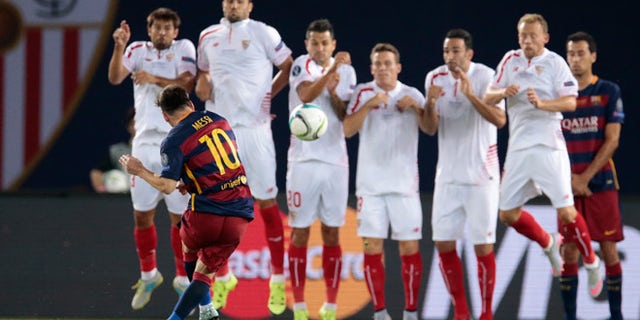 Barcelona's Lionel Messi, foreground, shoots a free kick to score his sideâs second goal during the UEFA Super Cup soccer match between FC Barcelona and Sevilla FC in Tbilisi, Georgia, on Wednesday, Aug. 12, 2015.