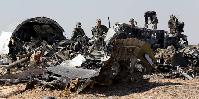 Military investigators from Russia stand near the debris of a Russian airliner at the site of its crash last November.
