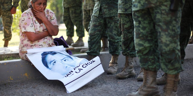 De moeder van de vermiste student Adan Abarajan de la Cruz zit aan de voet van soldaten buiten een militaire basis tijdens een protest van de families van 43 vermiste studenten over de vermeende verantwoordelijkheid van het leger of het uitblijven van een reactie op de verdwijning van de studenten in Iguala, Mexico. 