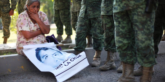 The mother of missing college student Adan Abarajan de la Cruz sits at the foot of soldiers outside a military base during a protest by the families of 43 missing students over the army's alleged responsibility or lack of response to the students disappearance in Iguala, Mexico. 