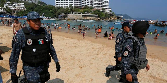 Federal police officer patrol Caleta beach crowded with local residents and tourists in Acapulco, Mexico, Friday, May 13, 2016. The city of Acapulco and Guerrero state in general have experienced a wave of violence attributed to warring drug gangs. On Saturday Mexican authorities say three men were gunned down, in a tourist-hotel quarter of the Pacific resort city. (AP Photo/Enric Marti)