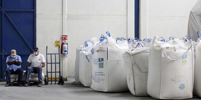 Workers sit next to bags containing sugar at the San Francisco Ameca sugar factory in the town of Ameca, Jalisco.