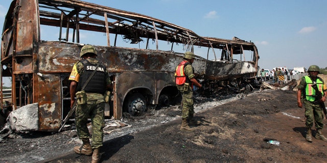 April 13, 2014: Soldiers guard the site where a passenger bus slammed into a broken-down truck and burst into flames near the town of Ciudad Isla in the Gulf state of Veracruz, Mexico. Dozens of people traveling on the bus to Mexico City burned to death inside the bus.
