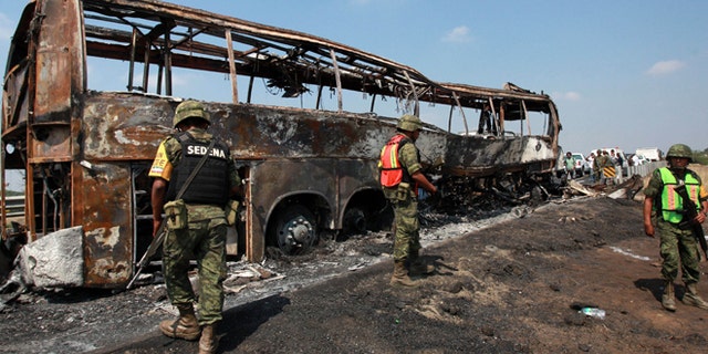 April 13, 2014: Soldiers guard the site where a passenger bus slammed into a broken-down truck and burst into flames near the town of Ciudad Isla in the Gulf state of Veracruz, Mexico. Dozens of people traveling on the bus to Mexico City burned to death inside the bus.