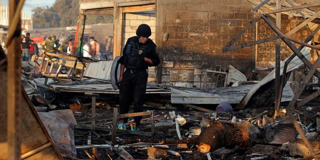A Mexico State policeman looks through the scorched ground of the open-air San Pablito fireworks market, in Tultepec, outskirts of Mexico City, Mexico, Tuesday, Dec. 20, 2016.