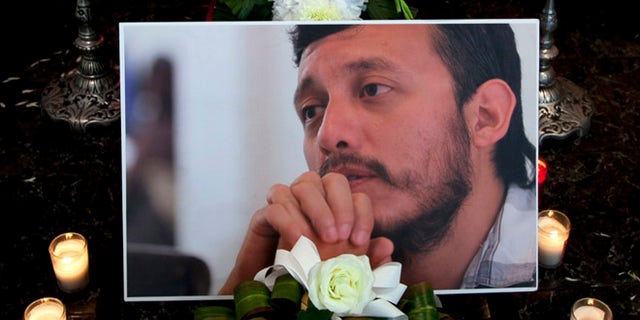 A photograph of murdered photojournalist Ruben Espinosa sits among flowers and candles in front of his casket inside a funeral home before his wake begins in Mexico City, Monday, Aug. 3, 2015.