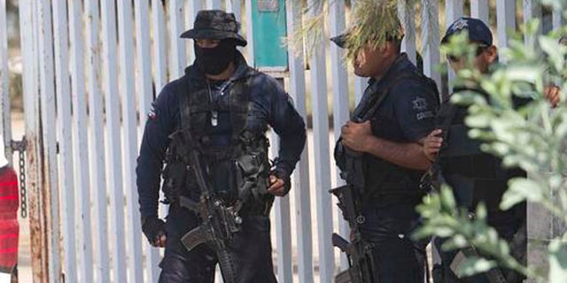 FILE - In this May 22, 2015, file photo, Mexican state police stand guard near the entrance of Rancho del Sol, where a shootout with the authorities and suspected criminals happened near Vista Hermosa, Mexico. Mexico's National Human Rights Commission said on Thursday, Aug. 18, 2016, that it has concluded that 22 people were arbitrarily executed by federal police during the event. Commission President Luis Raul Gonzalez Perez said their investigation revealed a range of human rights abuses on the part of government forces. (AP Photo/Refugio Ruiz, File)