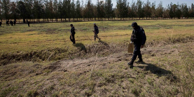 Police comb a field for evidence in the Rancho del Sol, a ranch in the municipality of Ecuandureo, Mexico, Saturday, May 23, 2015. The latest in a series of clashes between Mexican authorities and a powerful, fast-growing drug cartel turned into the deadliest confrontation in recent memory, with 42 suspected gang gunmen and one Federal Police officer killed on Friday during a three-hour firefight at this remote western ranch. (AP Photo/Eduardo Verdugo)