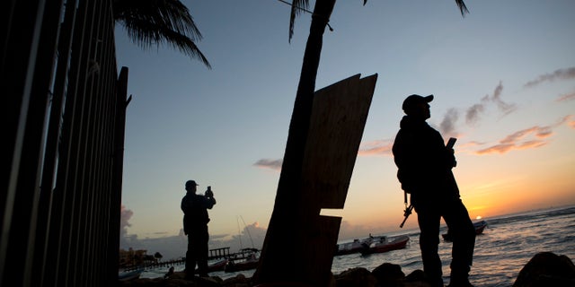 Municipal police watch the sunrise as they stand guard on the beach in front of the Blue Parrot club, a day after a deadly early morning shooting, in Playa del Carmen, Mexico, Tuesday, Jan. 17, 2017.