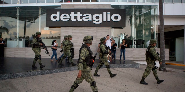 Soldiers walk outside Plaza Las Americas mall following reports of gunfire in Cancun, Mexico, Tuesday, Jan. 17, 2017.