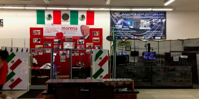 In Phoenix, there is a make-shift booth set up in a Latino central market that functions as an information booth for Mexican voters wanting to mail-in their ballots.