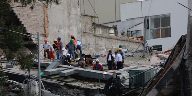 People clear rubble after an earthquake hit Mexico City, Mexico September 19, 2017.