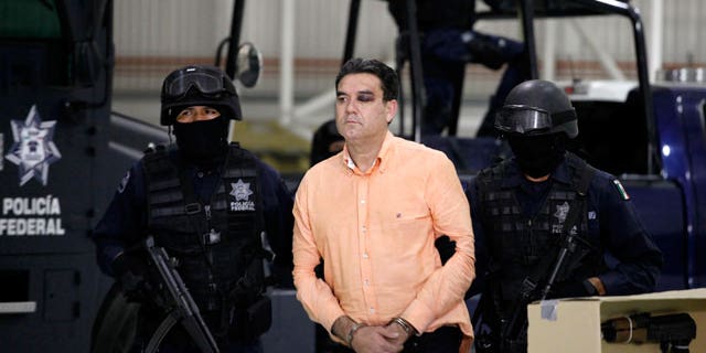 Police officers escort suspected drug trafficker Manuel Fernandez as he is presented to the media at the federal police headquarters in Mexico City, Monday Nov. 8, 2010. According to federal police Fernandez, an alleged member of the criminal organization led by Joaquin Guzman Loera, aka "El Chapo Guzman", was arrested Sunday in the northern city of Culiacan, Sinaloa state.