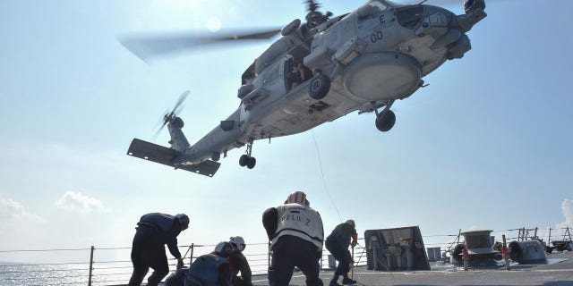 U.S. Navy Sailors participate in a medical training exercise on the deck of the Arleigh Burke-class guided missile destroyer USS Lassen (DDG 82) with an MH-60R Seahawk helicopter, in the South China Sea, October 28, 2015, provided by the U.S. Navy.