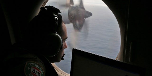 In this March 22, 2014, file photo, flight officer Rayan Gharazeddine scans the water in the southern Indian Ocean off Australia from a Royal Australian Air Force AP-3C Orion during a search for the missing Malaysia Airlines Flight MH370.