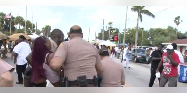 Police carrying away a woman who appeared to be hurt.