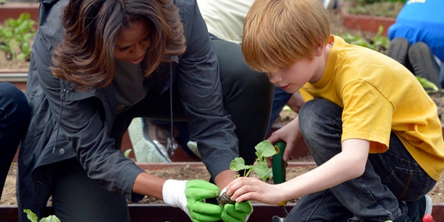 April 2, 2014: First lady Michelle Obama and Bancroft Elementary School student Silas Stutz plant broccoli in the White House Kitchen Garden in Washington.
