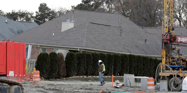 In this Jan. 4, 2017 file photo, a construction worker walks by a home collapsed by a sinkhole in Fraser, Mich.