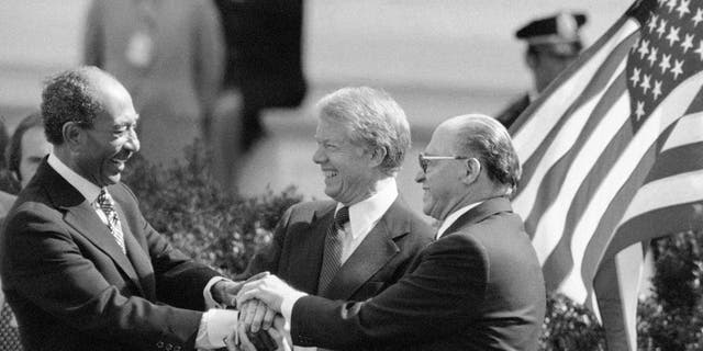 Egyptian President Anwar Sadat, left, President Jimmy Carter, center, and Israeli Prime Minister Menachem Begin clasp hands to symbolize their mutual pleasure upon signing Middle East Peace Treaty at the White House in Washington, March 27, 1979. (AP Photo)