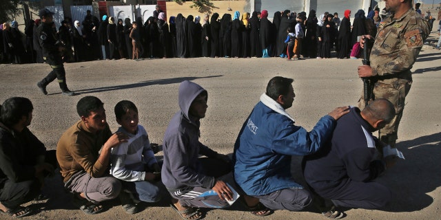 Iraqi citizens que to receive food supplies, at al-Arbajiyeh neighborhood, in Mosul, Iraq, Saturday, Nov. 19, 2016.